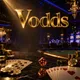 Vodds online casino hero banner with gold chips, playing cards, and ruby dice on dark marble under cinematic golden and sapph