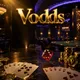 Vodds online casino hero banner with gold chips, playing cards, dice on dark marble under cinematic casino lighting