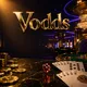 Vodds online casino hero banner with gold chips, playing cards, and ruby dice on dark marble under cinematic golden and blue 